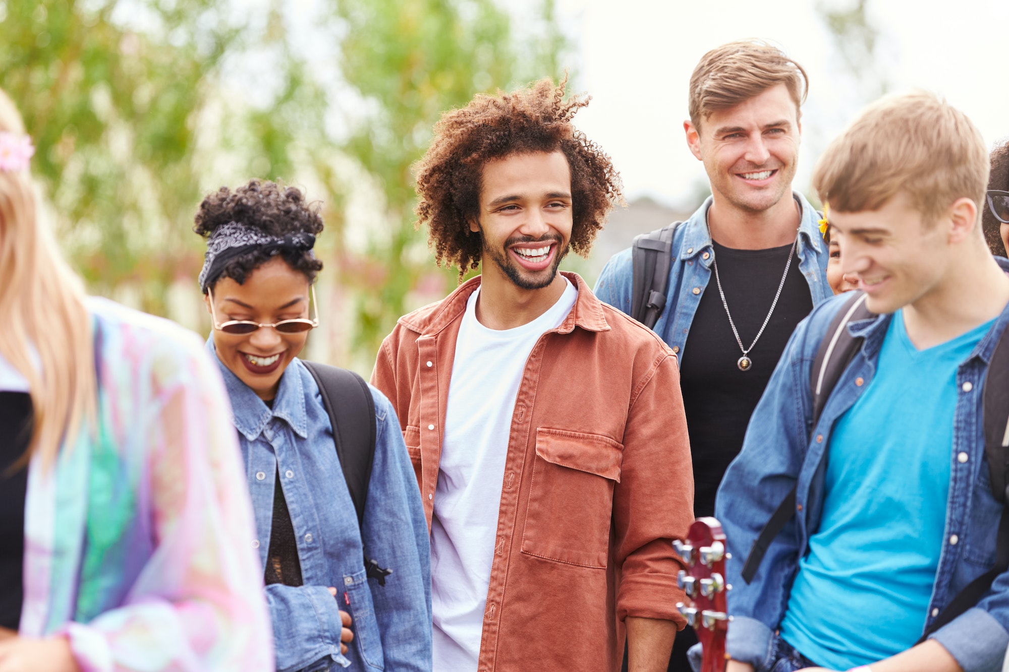 Group Of Young Friends Waiting Behind Barrier At Entrance To Music Festival Site